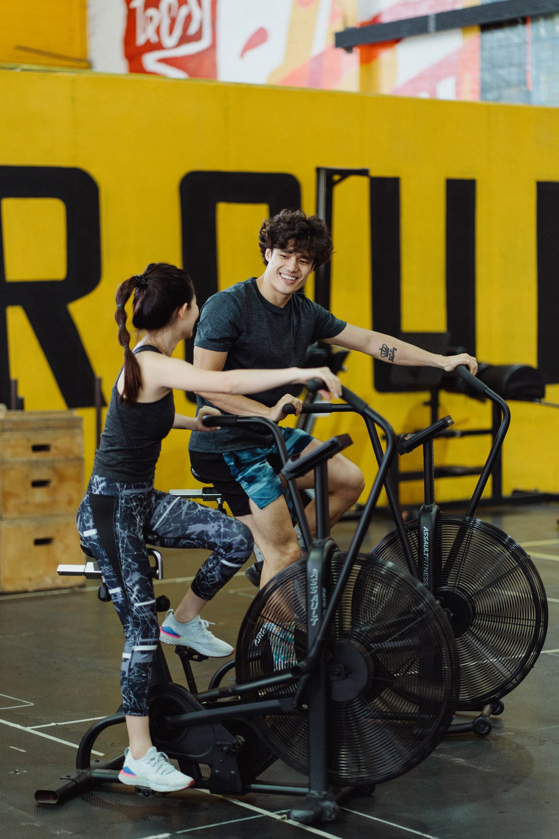 Two people training side by side on stationary bikes, comparing upright and recumbent exercise bikes in South Africa